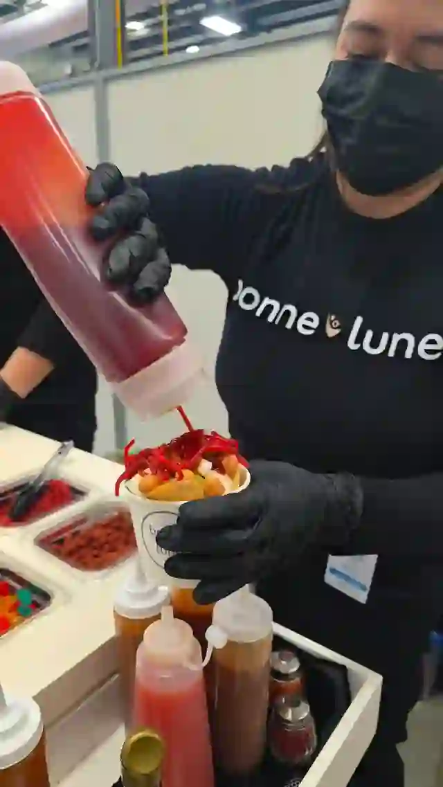 Miembro del equipo de Bonne Lune preparando un vaso de snacks con salsas